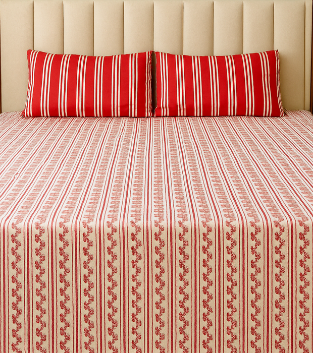 Bed with red and white striped bedding and pillows against a neutral wall.